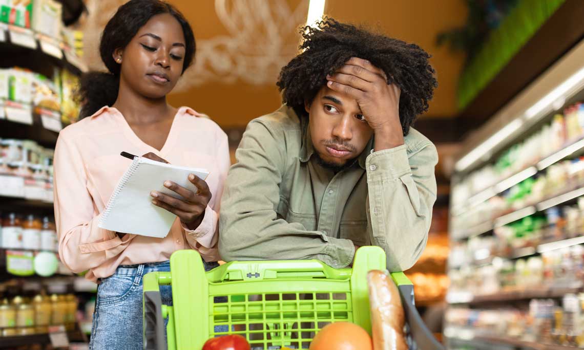 Frustrated couple shopping at store with shopping cart and shopping list